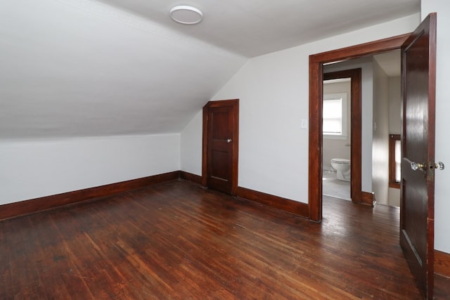 additional living space featuring baseboards, lofted ceiling, and dark wood-style floors
