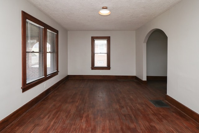 spare room featuring a textured ceiling, wood finished floors, visible vents, and baseboards