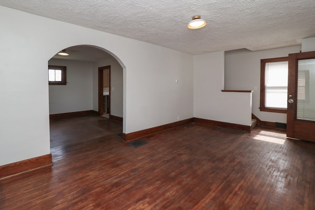 spare room featuring a wealth of natural light, visible vents, baseboards, and wood-type flooring
