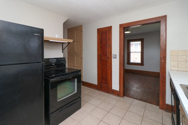 kitchen with black appliances, light tile patterned floors, light countertops, and baseboards