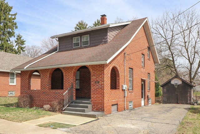 view of front of property with a porch, a shingled roof, a chimney, an outdoor structure, and a storage unit