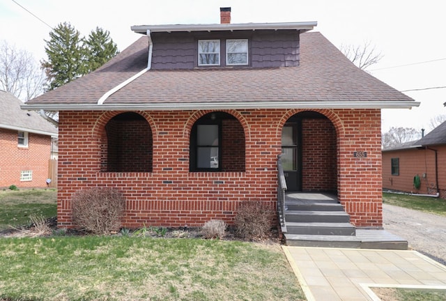 view of front of home featuring brick siding and roof with shingles