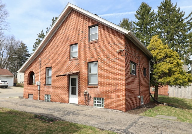 rear view of house with brick siding, driveway, and a garage