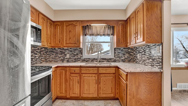 kitchen with a wealth of natural light, appliances with stainless steel finishes, decorative backsplash, and sink