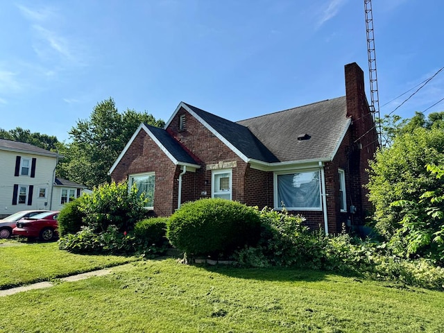 625 Grove Ave, Galion, OH 44833 - view of front of house with brick siding, a chimney, a front yard, and roof with shingles