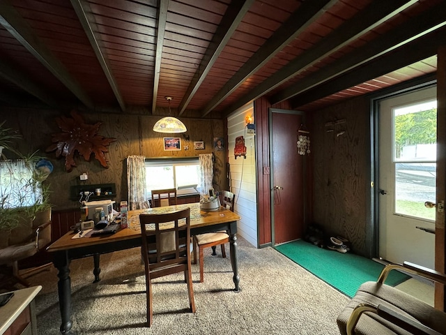 dining space featuring carpet, wood walls, beam ceiling, and a wealth of natural light