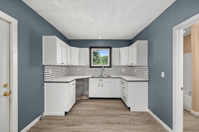 131 Sturges Ave, Mansfield, OH 44903 - kitchen with a textured ceiling, backsplash, white cabinets, and light wood-style flooring