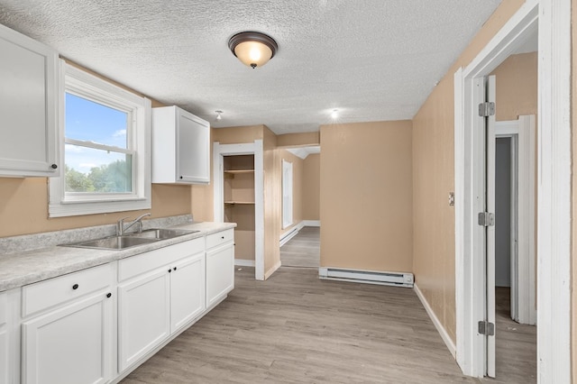 131 Sturges Ave, Mansfield, OH 44903 - kitchen featuring baseboard heating, white cabinetry, light countertops, light wood-style floors, and a textured ceiling