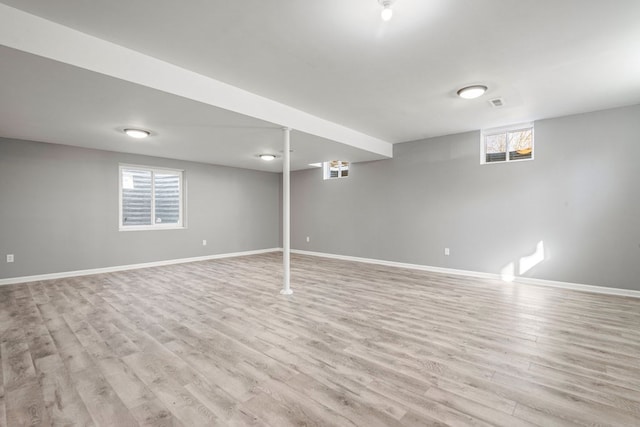 below grade area with visible vents, baseboards, and light wood-style flooring