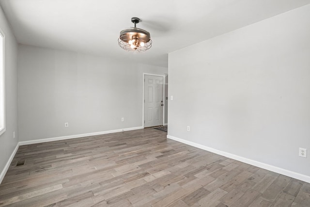 unfurnished room with visible vents, baseboards, and wood finished floors