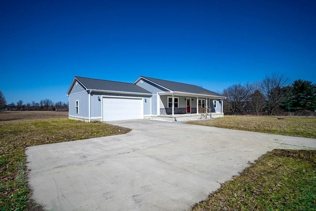 ranch-style house with a front yard, driveway, covered porch, a garage, and metal roof