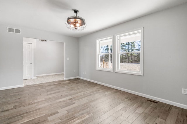 unfurnished room with visible vents, light wood-type flooring, and baseboards