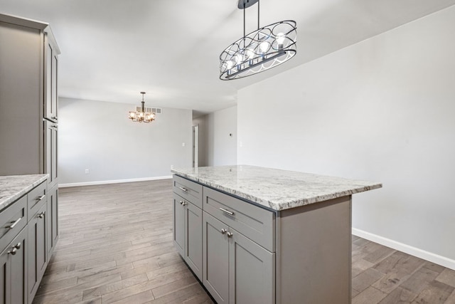 kitchen with a kitchen island, wood finished floors, gray cabinets, and hanging light fixtures