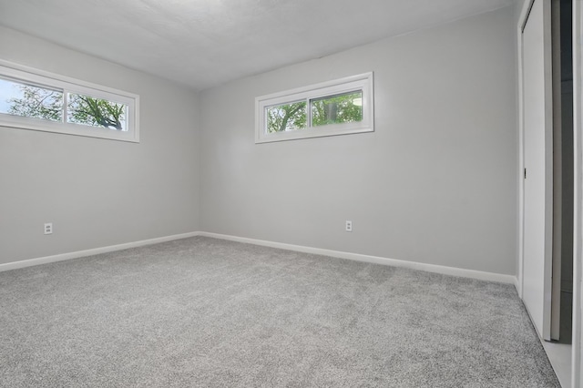 spare room with baseboards, light carpet, and a healthy amount of sunlight