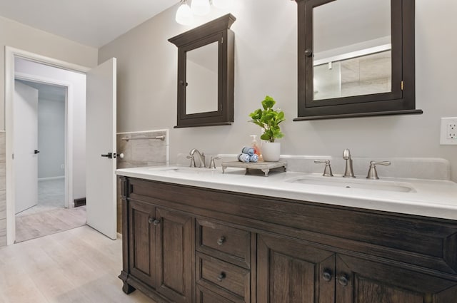 bathroom featuring double vanity, a sink, and wood finished floors