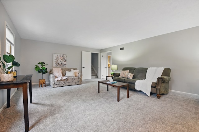 carpeted living room featuring baseboards and stairs