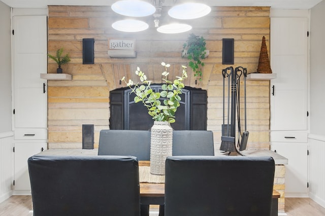 dining space featuring wooden walls, light wood finished floors, and a decorative wall