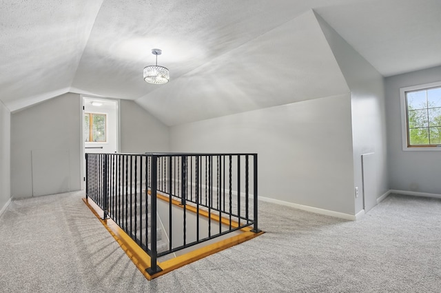 bonus room featuring carpet flooring, a chandelier, baseboards, and vaulted ceiling