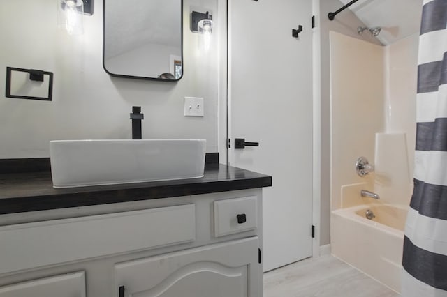 bathroom featuring vanity, baseboards, wood finished floors, and shower / bath combination with curtain