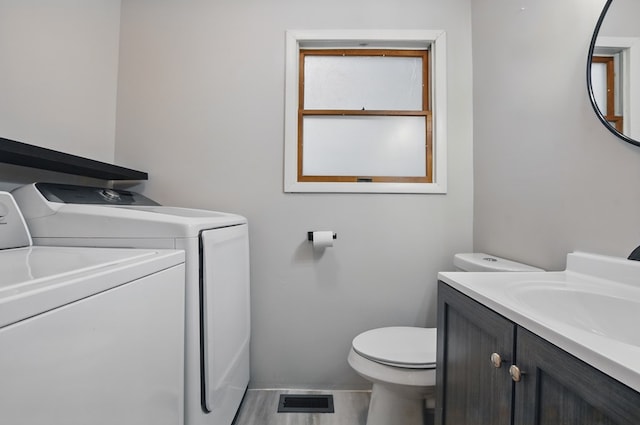 half bathroom featuring independent washer and dryer, toilet, visible vents, and vanity