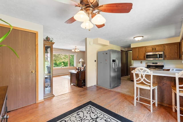 424 Day Rd, Mansfield, OH 44903 - kitchen featuring appliances with stainless steel finishes, light wood-style flooring, light countertops, ceiling fan, and brown cabinetry
