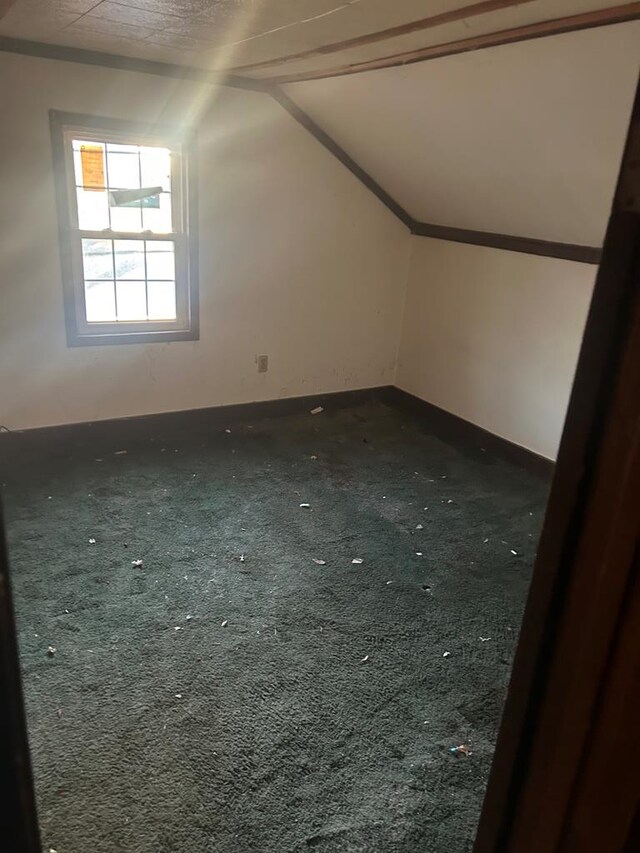 bonus room with lofted ceiling and dark carpet