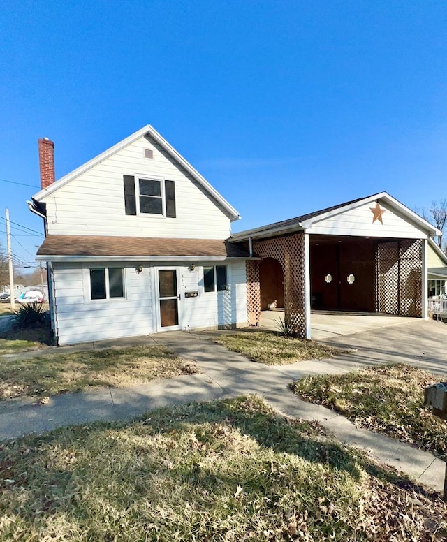 view of front of house with a chimney, an attached carport, and concrete driveway