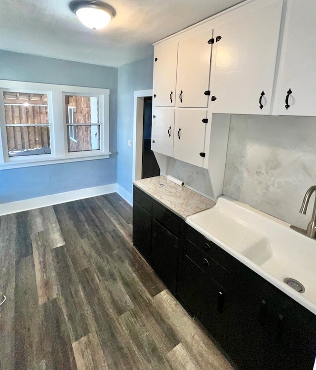 kitchen featuring light countertops, dark cabinets, dark wood-style flooring, and white cabinetry