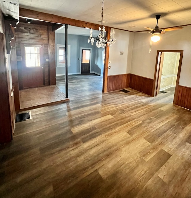 unfurnished dining area featuring a wainscoted wall, wood finished floors, visible vents, and wood walls