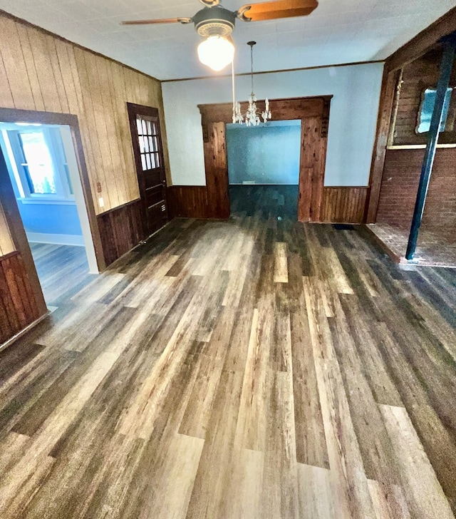 unfurnished dining area featuring wooden walls, wood finished floors, a wealth of natural light, and wainscoting