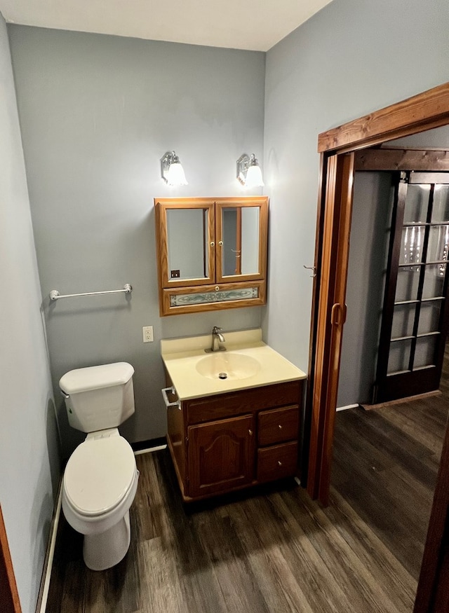 bathroom featuring toilet, vanity, and wood finished floors