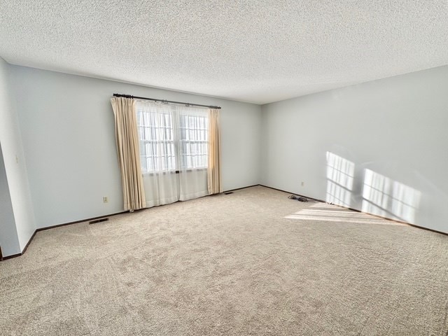 unfurnished room featuring light carpet and a textured ceiling