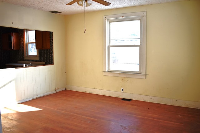 spare room featuring hardwood / wood-style floors, ceiling fan, radiator heating unit, and a textured ceiling