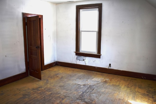 spare room with dark wood-type flooring and lofted ceiling