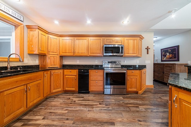 kitchen with dark stone counters, recessed lighting, dark wood-style floors, stainless steel appliances, and a sink