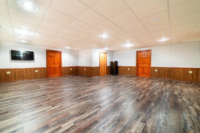 interior space featuring a drop ceiling, wainscoting, and wood finished floors