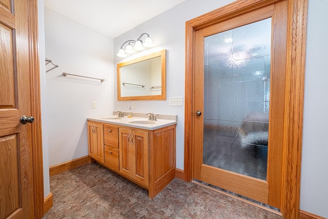 bathroom featuring a sink, baseboards, and double vanity