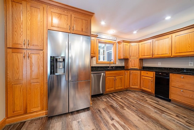 kitchen with dark stone countertops, a sink, dark wood-style floors, recessed lighting, and stainless steel appliances