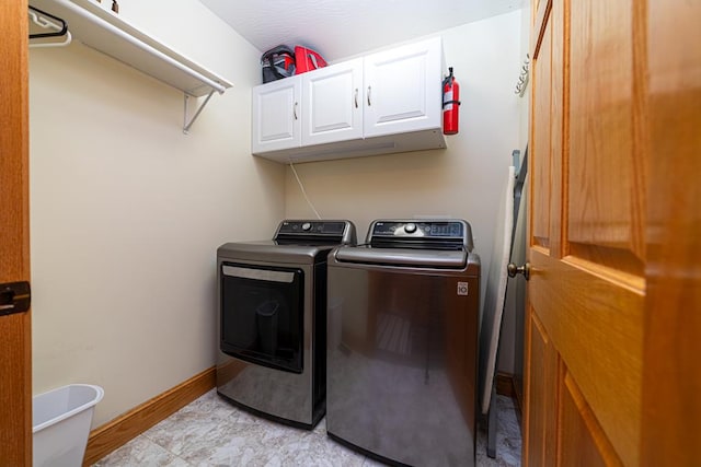 laundry area featuring separate washer and dryer, cabinet space, and baseboards