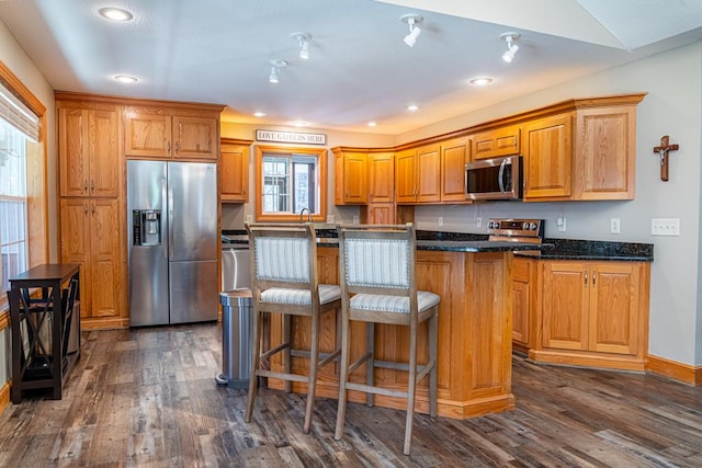 kitchen featuring a breakfast bar area, a kitchen island, appliances with stainless steel finishes, and dark wood finished floors