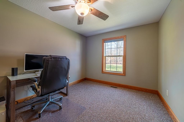 carpeted office space with visible vents, a textured ceiling, baseboards, and a ceiling fan