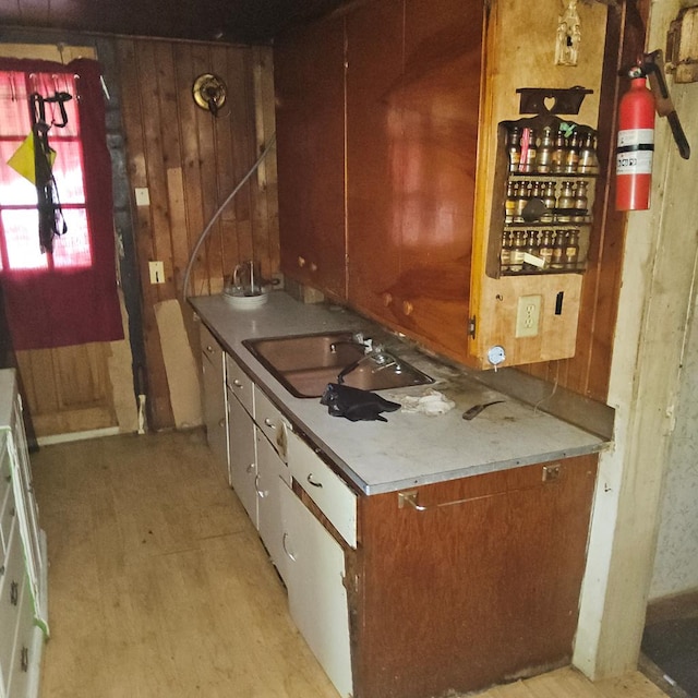 741 Burger Ave, Mansfield, OH 44906 - kitchen featuring a sink, wooden walls, brown cabinetry, and light wood-style flooring