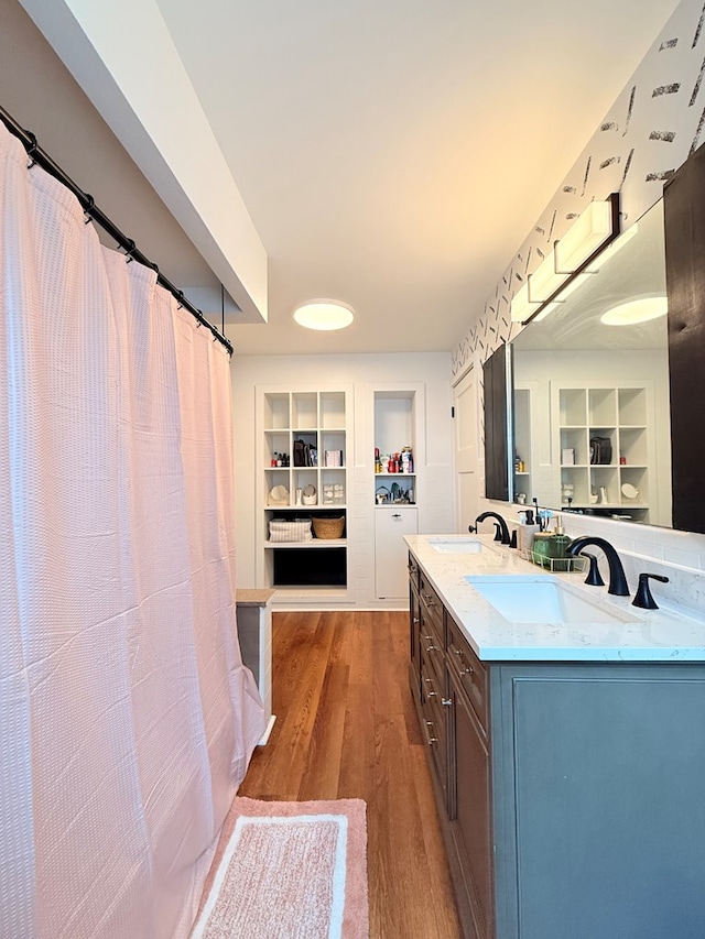 full bath with built in shelves, wood finished floors, double vanity, and a spacious closet