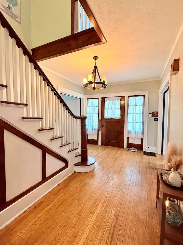 entryway with a chandelier, wood-type flooring, stairs, crown molding, and baseboards