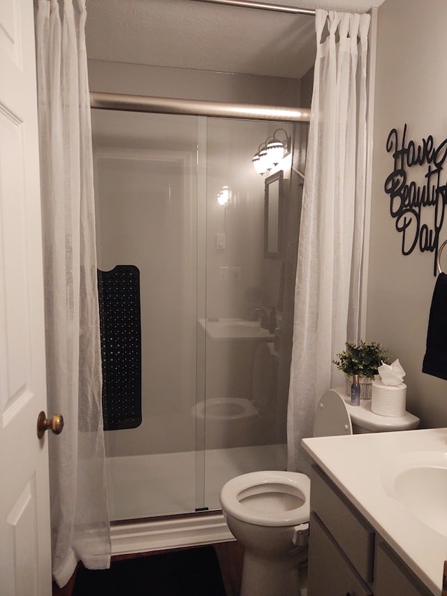 full bath with vanity, a stall shower, and toilet