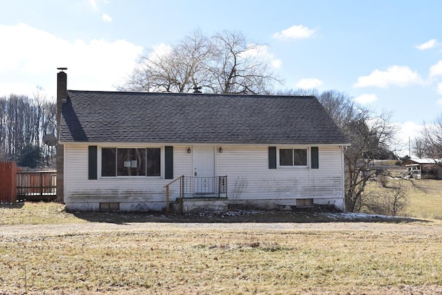 view of front of house featuring roof with shingles, a chimney, and a front yard