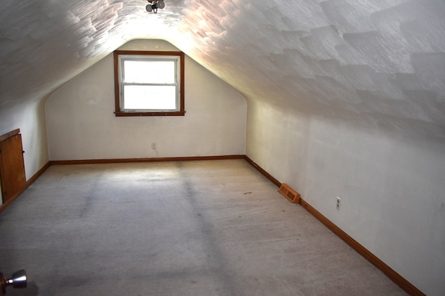 bonus room with baseboards, visible vents, vaulted ceiling, and light colored carpet