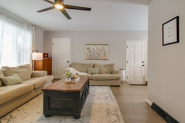 living room with a ceiling fan, baseboards, and wood finished floors