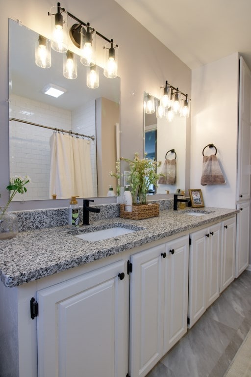 full bathroom with double vanity, curtained shower, and a sink
