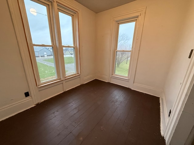 unfurnished room featuring a wealth of natural light and dark hardwood / wood-style floors